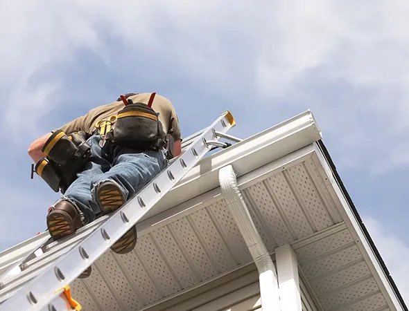 A man climbs a ladder to reach the roof, illustrating the task of roofing and building upkeep.